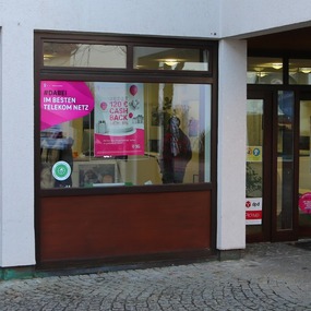 Telekom Shop mit großen Werbeplakaten zu 5G, MagentaTV und Cashback Aktionen im Schaufenster.